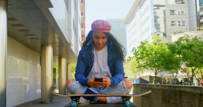 Female dancer with skateboard using mobile phone in the city 4k