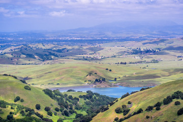 View towards San Antonio reservoir surrounded green hills; Pleasanton and Mt Diablo in the background, Alameda county, San Francisco bay area, California