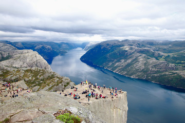 Several hikers enjoying the views in the summit of the Pulpit Rock (Preikestolen), one of the world’s most spectacular viewing points . A plateau that rises 604 meters above the Lysefjord, Norway.