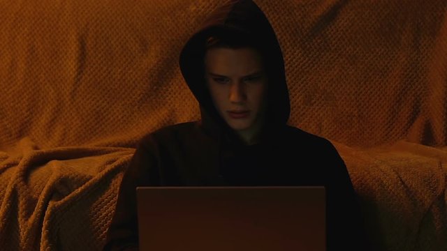Young man playing video game on laptop at night, technique problems, close up