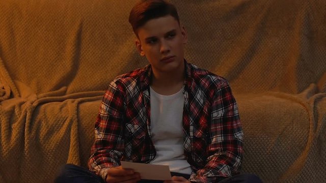 Unhappy young student looking at photocard, missing parents and home, depression