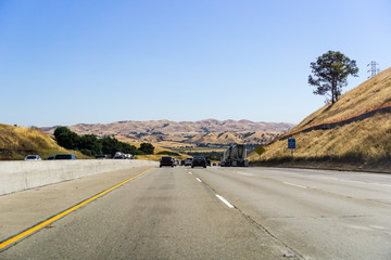 Driving on the freeway in east San Francisco bay area on a sunny summer day; golden hills in the background; California