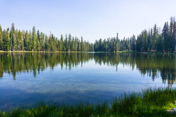 Fototapeta na wymiar Coniferous trees forest reflected in the calm waters of Summit Lake, Lassen Volcanic National Park, Northern California