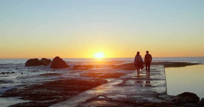 Couple walking hand in hand on the pier during sunset 4k