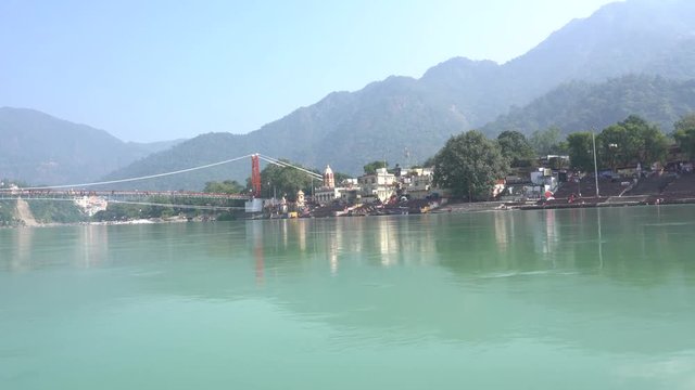 View from the boat that floats on the water river Ganges near Laxman Jhula footbridge, Rishikesh, India