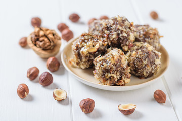 Scattered on a white table hazelnuts and sweets of grated nuts and dried fruits on a white table.