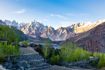 Glasschilderij Gasherbrum Tupopdan mountain also known as Passu Cones or Passu Cathedral, big rocks all over the place and blue crystal of Hunza river at sunset time ,Northern of Pakistan