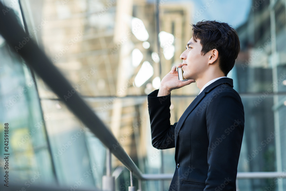 Wall mural business man talking on the phone with city building background