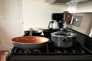 Modern stainless steel gas stove oven in a home with various cookware.