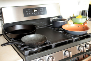 Modern stainless steel gas stove oven in a home with various cookware.