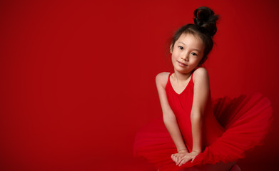 Cute little girl ballerina in beautiful dress is dancing on red 