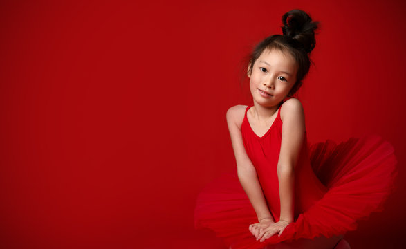 Cute little girl ballerina in beautiful dress is dancing on red 