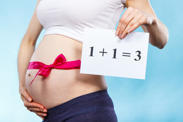 Woman in pregnant with pink ribbon on belly and inscription 1+1=3, concept of extending family
