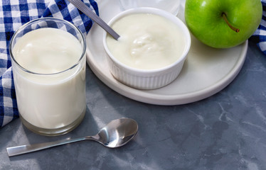 Two cups of yogurt and an apple as a healthy breakfast. Yogurt made from milk fermented by added...