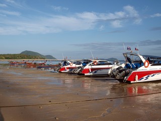 Speedboats moored in the sand on the beach. Low tide at a tropical resort. Cruise speedboats are waiting for tourists on the sea coast. Popular resort. Trip to an islands, service