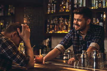 Young bartender standing at bar counter serving customer cheering up