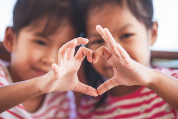 Two cute asian child girls making heart shape with hands together with love