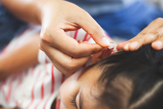 Parent helping her child perform first aid ear injury after she has been an accident