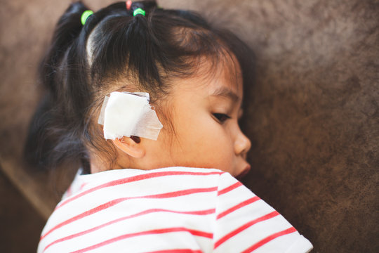 Asian child girl injured on the ear. Child's ear with bandage after she has been an accident.