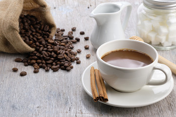 Coffee cup on wooden table in the morning with coffee bean, cube  sugar and cinnamon. - image