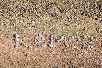 The word Kemer is laid out by pebbles on the beach of the Mediterranean Sea