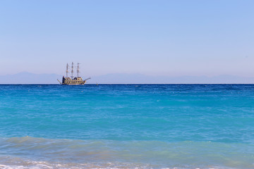 The excursion Piracy tourist ship floats across the Mediterranean Sea in the distance. Turkish sea landscape