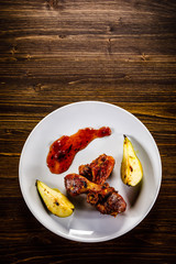 Grilled chicken drumsticks with pear on wooden background