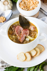 Thick pea soup with smoked meats in a white plate