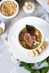 Thick pea soup with smoked meats in a white plate
