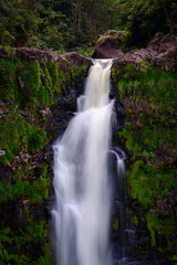 A long exposure of a waterfall flowing past green mossy rocks