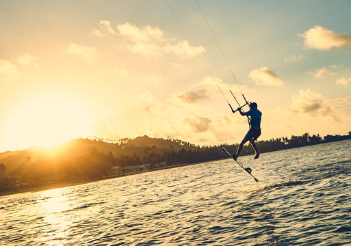 Young man kite boarder jumps over the sea at sunset           