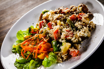 Grilled meat, white rice and vegetables on wooden table