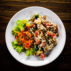 Grilled meat, white rice and vegetables on wooden table
