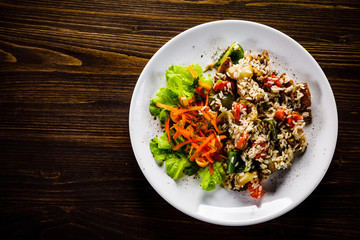 Grilled meat, white rice and vegetables on wooden table