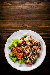 Grilled meat, white rice and vegetables on wooden table