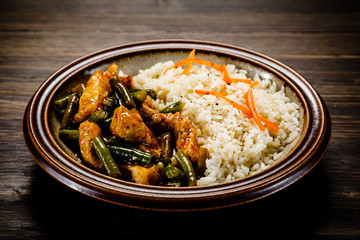Grilled meat, white rice and vegetables on wooden table