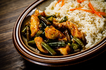 Grilled meat, white rice and vegetables on wooden table