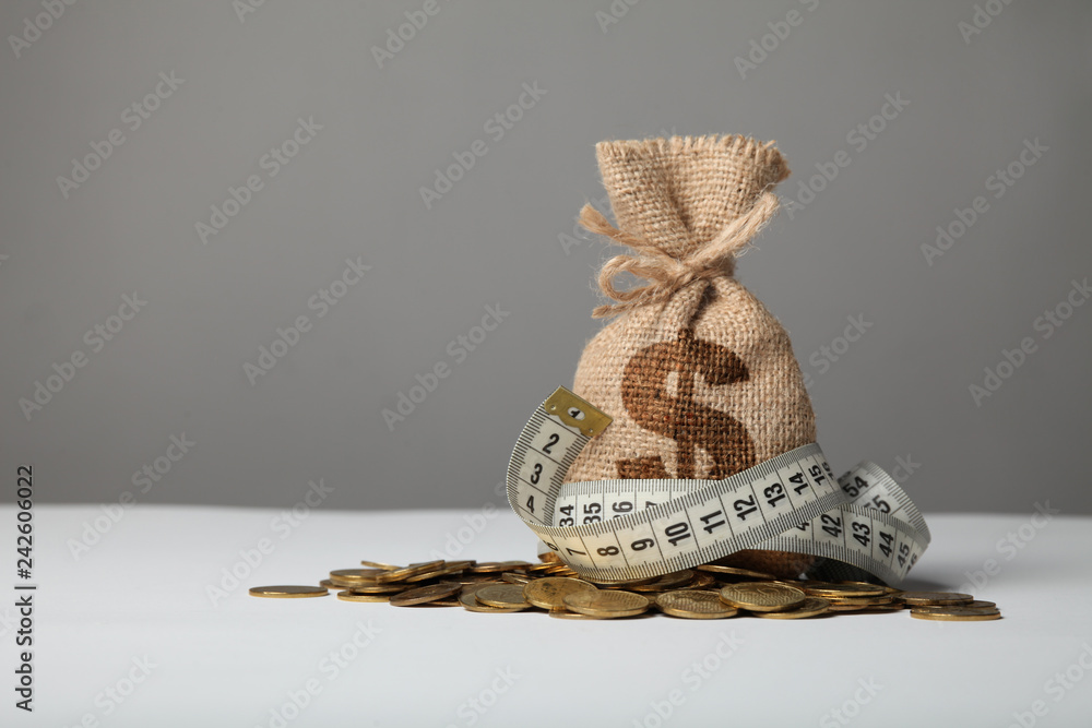 Wall mural bag with money and measuring tape on gold coins. lack of money, poverty and savings.