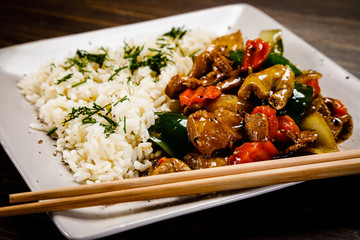 Grilled meat, white rice and vegetables on wooden table