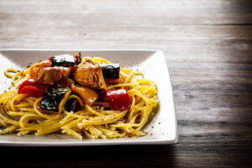 Roasted meat, pasta and vegetables on wooden background