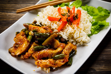 Grilled meat, white rice and vegetables on wooden table