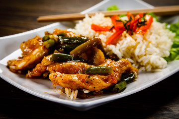 Grilled meat, white rice and vegetables on wooden table
