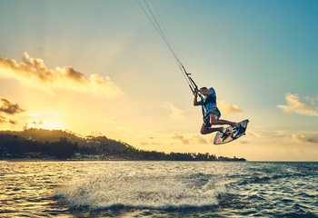 Young man kite boarder jumps over the sea at sunset            - obrazy, fototapety, plakaty