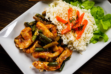 Grilled meat, white rice and vegetables on wooden table