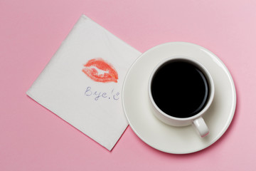 Obraz na płótnie Canvas Napkin with a kiss and coffee cup on pink background.