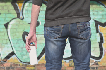 Graffiti artist with a spray can in his hand. Back view