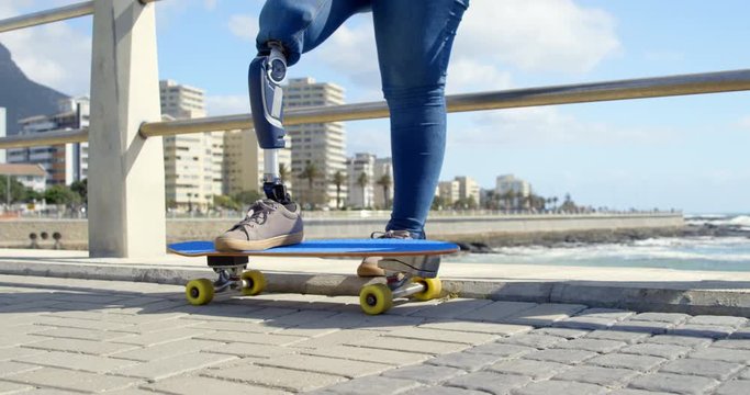 Low section of disabled woman standing with skateboard on promenade 4k 