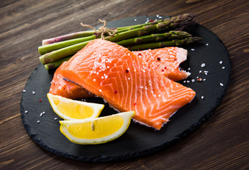 Fresh raw salmon fish served on black stone on wooden table