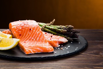 Fresh raw salmon fish served on black stone on wooden table