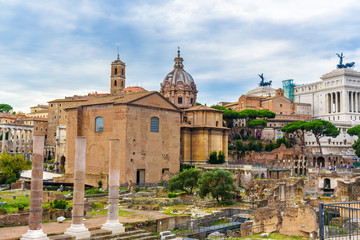 Fototapeta na wymiar Ruins of Roman Forum. Curia Julia, Roman columns and church of Santi Luca e Martina. Rome. Italy